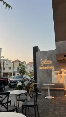 This video offers a serene, real-time look inside Sequence Coffee, showcasing its stylish outdoor seating, modern branding, and inviting ambiance during golden hour. Viewers see the café's unique architectural details, including its illuminated logo and artistic sculptures, set against a backdrop of a quiet street with passing cars and nearby buildings. The calm atmosphere highlights the café as a contemporary urban retreat perfect for coffee lovers and those seeking a peaceful spot to relax. by @sequence-coffee with original sound