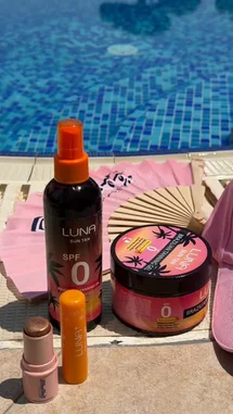 A serene poolside scene showcases a curated collection of Luna Sun Tan sun care products, including a spray bottle, tanning balm, and lip balms. The setting evokes a relaxing summer day by the water, perfect for enjoying beauty essentials in a tranquil environment. by @bx301a with BARA🇧🇷🔥🌬️ by Contains: Ritmadinha Trajado de Lacoste - MC VN Cria
