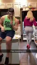 In a brightly lit home kitchen, a man in a 'COOL BRO' tank top sits on the counter laughing uncontrollably. A woman in a pink hoodie opens the refrigerator, turns around, and sees his reaction, prompting her to laugh as well. The moment captures a spontaneous and funny interaction between the two individuals. by @chriscolditz with Original Sound by chriscolditz