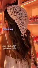 A woman models a delicate pink crochet headscarf adorned with starfish and mermaid charms, styled over long wavy hair. She wears a white spaghetti strap dress and carries a matching pink tassel bag. The setting is a warm, pink-lit boutique, creating a soft, romantic aesthetic. This look is perfect for spring, summer, or boho-chic fashion enthusiasts. by @bx301a with 💖 by Contains: Sex on the Beach - PARTYNEXTDOOR