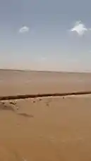 This video captures a journey across a vast desert landscape under a clear sky. A vehicle is seen traveling along a dirt road, emphasizing the expansive and remote environment. by @manahi.20 with manahi.20 by Original Sound