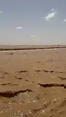 This captivating footage takes you on a journey across a vast desert landscape under a clear blue sky. The camera glides over the textured, sandy terrain, revealing the natural beauty and isolation of the arid environment. In the distance, a few structures and a vehicle can be seen, hinting at human presence amidst the expansive wilderness. The serene atmosphere and stunning scenery make this a perfect visual experience for anyone interested in desert exploration and nature photography. by @manahi.20 with manahi.20 by Original Sound