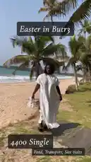 A woman in a long white dress walks along a sandy path next to a beach lined with palm trees. She turns and smiles at the camera before playfully spinning around, her dress billowing in the breeze. by @naa.ayele911 with Original Sound by naa.ayele911