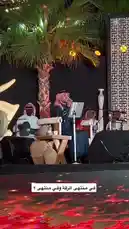 Experience the vibrant atmosphere of an evening 'Jalsah' cultural event. This performance features traditional musicians dressed in national attire, including keffiyehs, playing authentic instruments like the darbuka. A lead singer performs passionately into a microphone while seated on stage, accompanied by his band. The setting includes a palm tree backdrop, elegant lighting, and a dynamic red LED floor display, creating an immersive and festive ambiance perfect for a live concert or special gathering. by @jalsahevent with jalsahevent by Original Sound