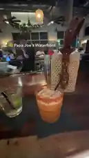 Montell Jordan 님이 만든 This Is How We Do It 포함 @itsma_bitchezz 님이 만든 A close-up view of a vibrant orange cocktail with a spicy rim and a classic gin and tonic, served at Papa Joe's Waterfront. The cozy bar ambiance, complete with hanging lights and a stylish woven handbag, sets the stage for a relaxed evening. This scene captures the essence of a casual night out, perfect for sharing on social media.
