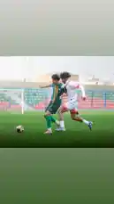 This dynamic clip captures a live-action moment from a youth soccer training session at Al-Rawdah FC, a Saudi Arabian football club. Two young athletes—one in a green kit and another in white—are intensely competing for possession of the ball on a well-maintained grass pitch. Their focused expressions and athletic movements highlight the competitive spirit and skill development central to youth sports. In the background, stadium seating and goalposts suggest a professional training environment. The scene showcases dedication, teamwork, and the pursuit of excellence in Saudi football. by @alrawdahclub with original sound