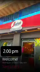 This video captures the inviting entrance of a Segafredo Zanetti Espresso café in Hebron. The vibrant red and blue storefront is illuminated, welcoming patrons. On-screen text reads '2:00 pm' and 'Welcome! Wishing you a lovely Friday with Segafredo,' setting a warm, commercial tone. The scene is static, showcasing the brand's presence in a specific location. by @segafredohebron with Original Sound by segafredohebron