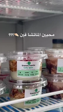 A close-up view of protein-packed granola matcha cups neatly arranged on a refrigerator shelf. The labels clearly display nutritional information like calories, protein, fat, and carbs, highlighting their suitability as a convenient and healthy meal or snack option. by @proteinz_sa with original sound