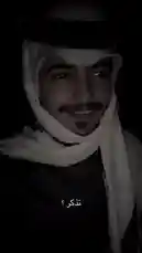 In a dimly lit setting, a person wearing traditional attire including a white headscarf and dark clothing is shown in close-up. The individual maintains a calm expression, looking directly into the camera. The Arabic text 'تتذكر؟' (Do you remember?) is overlaid, creating a sense of nostalgia or prompting a memory. This atmospheric clip captures a quiet, contemplative moment. by @c0_hn with Original Sound by c0_hn