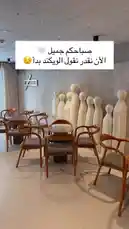 This video offers a behind-the-scenes look at Sequence Coffee, showcasing its stylish interior design. The modern space features minimalist wooden chairs, sleek tables, and a unique artistic wall installation of white, abstract human figures. An Arabic text overlay reads 'We love you ❤️, we miss you so much,' adding a personal touch to the ambiance. by @sequence-coffee with For a good mood by 🪩✨