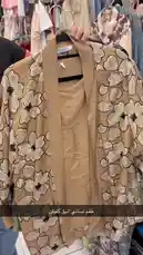 This video showcases a collection of stylish spring cardigans from كود اناقتي. The camera pans across various designs, highlighting beige, green, black, and light blue cardigans, all featuring prominent white floral patterns. Each piece is displayed on a hanger, revealing its design details and tag, suggesting a new arrival or fashion showcase. by @code.a3 with original sound