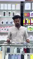 A knowledgeable sales associate at محل السوبر الذهبي للهواتف demonstrates various smartphones and accessories behind the counter. He highlights features like reverse charging and water resistance, showcasing different models including iPhones and Samsung Galaxy devices. The store's shelves are stocked with branded products, creating a professional tech retail environment. by @super_golden7 with Original Sound by super_golden7