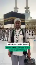 This image captures Saudi citizen Yaser Al-Khamsan during his Umrah pilgrimage in Makkah. He is pictured smiling in front of the Kaaba, wearing a white uniform shirt with a 'SCOUT' patch, a green and white neckerchief, and a cap. The background shows the grandeur of Masjid al-Haram with its towering minarets. A voice recites the Islamic declaration of faith, 'Allahu Akbar,' and 'La ilaha illallah,' setting a reverent tone for the sacred visit. by @y_alkhmsan with تكبيرات عشر ذي الحجة 🍃 by Contains: كبرو في الأنحاء والارجاء - صناع الأمل