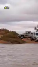 Witness a convoy of off-road vehicles, including Toyota Land Cruisers and a classic red pickup truck, navigating a shallow river crossing in a rugged desert landscape. This thrilling scene captures the essence of adventure travel and overlanding in Saudi Arabia. by @azozi.5562 with original sound