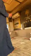 This video provides an authentic glimpse into a traditional Saudi Arabian home interior. It features men dressed in thobes and ghutras, relaxing on a large sofa and carpeted floor. The room is decorated with prominent Saudi Arabian symbols, including the national emblem on the wall, and is furnished with a hookah and fresh fruit. The scene captures a moment of casual conversation and hospitality, showcasing everyday life and cultural elements. by @manahi.20 with manahi.20 by Original Sound