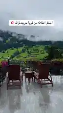This serene video captures breathtaking panoramic views of lush green Swiss mountains partially shrouded in mist. The scene opens on a charming balcony furnished with wooden chairs and vibrant pink flowers, offering a peaceful retreat overlooking a picturesque valley village. As the camera pans across the landscape, viewers are treated to the majestic beauty of the Alps, showcasing why Switzerland is a top destination for travelers seeking natural splendor. by @sahab-alalam with sahab-alalam by Contains: آيات|الفكر يا إنسان - ناصر السعيد