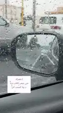 This video captures a serene moment from inside a car during a rainy day. Raindrops cling to the window and side mirror, creating a beautiful, blurred view of the world outside. A text overlay in Arabic appears, adding a contemplative and artistic touch to the scene. The atmosphere is peaceful, inviting viewers to pause and appreciate simple moments. by @om.louraa with original sound