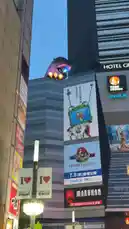 Witness a surreal moment in Tokyo where a giant purple Godzilla statue looms over a building adorned with a massive 'Toy Story 5' billboard. This unusual juxtaposition of pop culture icons creates a captivating street-level spectacle against the city skyline. by @junaidkhan with Original Sound by junaidkhan