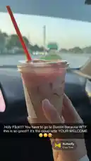 Crazy Town 님이 만든 Butterfly 포함 @rebeccaperi 님이 만든 A hand holds a pink-colored beverage in a clear plastic cup with a red straw, filmed from inside a car. The background shows a road and greenery through the windshield, suggesting a drive during the day. The drink appears to be a layered iced coffee or tea with ice cubes visible. An overlay displays the song 'Butterfly' by Crazy Town playing in the background.