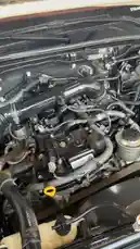 This video offers a detailed, close-up view of a car engine bay, starting with a tight shot of the intricate components like hoses, wires, and the oil cap. The camera then pulls back to reveal the entire white pickup truck parked inside a service garage, its hood propped open for inspection or repair. The ambient sound of machinery hums in the background, suggesting an active workshop environment. by @hawkar_service with Original Sound by hawkar_service