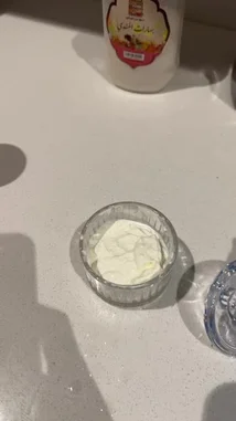 A close-up tutorial showing how to prepare a quick and elegant yogurt dessert. A hand adds chopped pistachios, then delicate saffron threads, to a bowl of creamy white yogurt. The process is simple and visually appealing, perfect for a healthy snack or light treat. by @alafasy81 with Original Sound by alafasy81