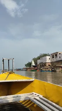 This first-person perspective video captures a peaceful boat ride along a river in India. From the bow of a yellow boat, viewers are taken on a scenic tour past a riverside temple complex and other boats, offering a glimpse into local life and architecture. by @guptaji_47 with guptaji_47 by Original Sound