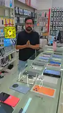 A salesperson from Super Golden Mobile Phones in Abu Dhabi gives a live product showcase, highlighting a clearance offer on various iPhones and Samsung devices. He displays different models, including the iPhone 15 Pro, iPhone 13 mini, iPhone 15 Plus, and Samsung S24 series, while announcing their prices and conditions. by @super_golden7 with Original Sound by super_golden7