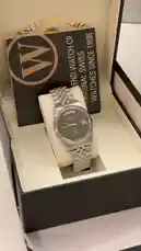 A close-up showcase of a silver West End Watch Co. watch with a grey dial, day-date complication, and stainless steel bracelet, presented in its branded box. A voiceover in Arabic describes the watch as a new model from the brand. by @lussowatches with Original Sound by lussowatches