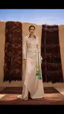 This captivating visual narrative by Moonlight Concept unfolds across two distinct scenes, celebrating the fusion of modern fashion and ancient cultural aesthetics. The journey begins in a serene, sun-drenched courtyard adorned with traditional rugs, where a model elegantly presents a contemporary beige gown with a unique asymmetrical hem and a decorative green sash. The scene then transitions to a breathtaking desert landscape, revealing a historic mud-brick settlement nestled among towering mountains. Here, another model embodies timeless grace in a flowing white ensemble accented with a vibrant purple belt and a delicate veil, standing amidst the architectural marvels of the past. This evocative piece masterfully blends high-fashion photography with rich cultural storytelling, creating a visually stunning experience. by @moonlight_q6r with original sound