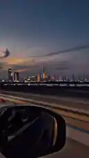 Experience the magic of Dubai's skyline from a moving car at twilight. This scenic drive captures the illuminated cityscape, including the iconic Burj Khalifa, as seen from a side mirror perspective. It's a perfect example of urban beauty and motion. by @moazzam with Kashish by Ashish Bhatia, Omkar Singh & Kashish Ratnani