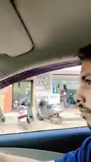 This first-person perspective video captures a journey through a lively street in India. The camera is mounted inside a car, showing the driver's hands on the steering wheel, the dashboard, and the view through the windshield. The route takes you past local shops, pedestrians, and other vehicles like motorcycles and auto-rickshaws under an overcast sky. A digital screen on the dashboard displays a person in a turban, adding a unique detail to the everyday commute. by @maddi_op with maddi_op by Original Sound