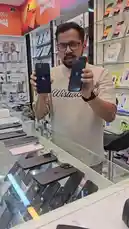 A salesperson at a mobile electronics store in Abu Dhabi presents various Apple devices, including iPhones 14 Pro, 16 Pro, and iPads, highlighting their battery percentages and prices. He displays phones like the iPhone 14 Plus, 15 Pro Max, and an iPad Air 16, emphasizing features such as scratch-free condition and included accessories. The store offers competitive pricing, with models ranging from 1,198 to 2,600 AED, all backed by warranties and screen protectors. by @super_golden7 with Original Sound by super_golden7