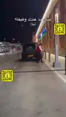 A nighttime scene unfolds at a modern shopping center where a man in a red vest approaches a sleek, matte-black Mercedes-Benz G-Class SUV. He opens the driver's side door, revealing a luxurious interior with striking red leather seats. The camera then moves inside, offering a close-up view of the steering wheel and dashboard, highlighting the vehicle's premium features. This glimpse into the world of high-end automotive luxury invites viewers to explore the details and craftsmanship of this powerful SUV. by @th4eb with Original Sound by th4eb