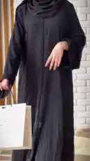 A model elegantly displays a black abaya adorned with subtle embellishments, holding a branded shopping bag from 'Khial Abaya'. The setting features a modern white brick wall and warm wooden accents, creating a chic backdrop. The model turns gracefully, highlighting the garment's design and flow. This fashion-focused clip is accompanied by Arabic pop music, enhancing the stylish and contemporary atmosphere. by @mohammed_aldrop with Original Sound by mohammed_aldrop