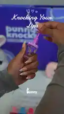 In this unboxing video, Bunny Knocks showcases her 'Knocking Your Lips' lip gloss collection. She opens the clear case to reveal five vibrant, candy-themed glosses. The video provides a close-up look at one of the individual bottles and demonstrates its wand applicator, offering viewers a detailed first look at the product. by @bunnyknocks with Original Sound by bunnyknocks
