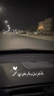 A nighttime drive through a quiet, well-lit street in Kuwait. The car moves forward steadily, passing under glowing streetlights and alongside modern buildings. Arabic text overlays the screen, adding a poetic or reflective element to the journey. The scene evokes a sense of calm and introspection during a solitary night drive. by @alafasy81 with original sound
