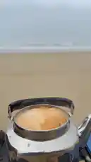 A serene beach picnic setup with tea, bread, and flowers on the sand, followed by calming ocean waves crashing on a misty day. by @nowaira-11 with موسيقى الحب by mihits