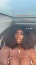 In this short clip, Nigerian social media personality Efia Adanals films herself from a low angle inside a car with the sunroof open. She has a large, voluminous afro hairstyle and is wearing a floral bikini top with red and green details. Her accessories include a gold pendant necklace and hoop earrings. Throughout the video, she poses for the camera, running her hands through her hair and making various expressions. by @naa.ayele911 with original sound