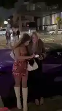 In this nighttime street scene, Jack Donnovan surprises two women with a large amount of cash. One woman, wearing a brown puffer jacket and glasses, reacts with visible shock and excitement as she is handed a thick stack of money. Her friend, in a sparkly pink dress, looks on in amazement. The scene is filled with onlookers capturing the moment on their phones, creating a viral-worthy spectacle. by @jackdonnovan with Original Sound by jackdonnovan