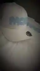 A close-up showcase of the latest white snapback hat from PACK'D. The camera focuses on the brand's signature light blue cloud-style 'PACK'D' logo embroidered on the front panel, highlighting its design details. by @pack.d with 30 Days by Born Trappy