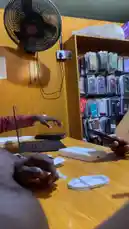 A close-up, first-person view shows a customer unboxing an iPhone 15 Pro Max and setting it up alongside an Apple Watch Series 8 at a Frekas Global electronics store. The scene captures the hands-on experience of receiving new Apple products, including connecting the charging cable, all within a retail environment filled with phone accessories. by @frekasglobal with Bejeweled by Taylor Swift