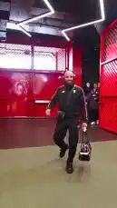 A group of Manchester United players, dressed in black tracksuits with white stripes, walk out of a tunnel onto a field. They are seen carrying bags and walking in formation, showcasing their team spirit before a match. by @manutd with Original Sound by manutd