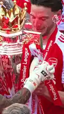 This celebratory scene captures Arsenal Football Club players hoisting the Premier League trophy amidst a shower of red confetti. Dressed in their iconic red jerseys, the team shares a moment of triumph. Text overlays highlight a key transfer, mentioning 'Declan Rice' and 'half price,' suggesting a narrative around a successful acquisition. The atmosphere is electric, with fans and players alike reveling in the victory. by @premierleague with Original Sound by premierleague