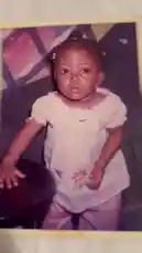This nostalgic photo captures a young Dhikrot 💗 in a candid moment from childhood. She is seen wearing a light-colored dress with a floral pattern and matching pants, her hair styled in pigtails adorned with small accessories. The image evokes a sense of innocence and family history. by @miji-bello with BIG MAMA☺️ by Mya.ak