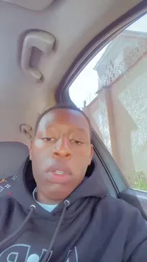 This is a candid, real-time selfie video filmed by fdlsage from inside their car. They are wearing a black hoodie and speaking directly to the camera, making various hand gestures like pointing and waving. The background shows a building outside the window and a distinctive Louis Vuitton patterned seat cover. The atmosphere is informal and conversational. by @fdlsage with fdlsage by Original Sound