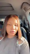 In this stylish car selfie, Big Erima showcases her trendy look with a grey cutout sweater adorned with silver embellishments. She points to her outfit while sitting in the driver's seat, giving viewers a glimpse into her personal style and fashion choices. by @eboggar1 with Original Sound by eboggar1
