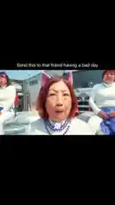A woman with red hair leads a group of dancers in a synchronized routine involving dog costumes and choreography. The performance includes scenes in a warehouse, on a grassy lawn, and in front of a large truck. The dancers wear matching white tops and blue patterned skirts, while the central performer sports cat ears and a pearl necklace. On-screen text in Chinese and English displays phrases like 'Be my dog' and 'Follow me.' The video features fast cuts, dynamic camera work, and humorous elements, such as people wearing blue ski masks and carrying trays. It culminates in a playful scene where the dancers interact with real dogs. by @christamic3 with Original Sound by christamic3