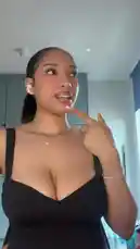 A woman, identified as Nika Dragon, showcases a stylish black dress with thin straps in a modern kitchen setting. She poses confidently, adjusting her hair and necklace while wearing white earbuds. The scene captures a moment of personal style and presentation. by @n8ka_122 with Original Sound by n8ka_122