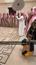 This video captures a vibrant traditional sword dance performance led by Bader Alodah. Dancers in authentic Saudi attire, including red-and-white checkered keffiyehs and ornate black and gold jackets, perform synchronized movements with swords and decorative shields. The event takes place in a grand hall with elegant carpeting, suggesting a formal cultural celebration. by @guruofmarketing with Original Sound by guruofmarketing