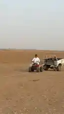 مناحي الرجباني يقود جرافة حمراء في صحراء واسعة، مُجرِّرًا شاحنة قديمة بيضاء تحمل ثلاثة أطفال. تظهر الشاحنة علامة 'TECO' على الجانب. يبتسم الأطفال ويستمتعون بالرحلة، بينما يمرّ الفريق بجانب مقطورة كبيرة وشاحنة نفطية. المشهد يعكس لحظة مغامرة ومرح في البيئة الصحراوية. by @manahi.20 with manahi.20 by Original Sound